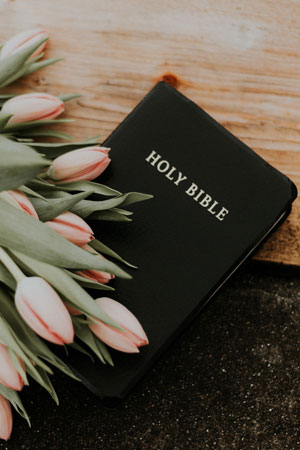 An open Bible resting beside a spray of flowers